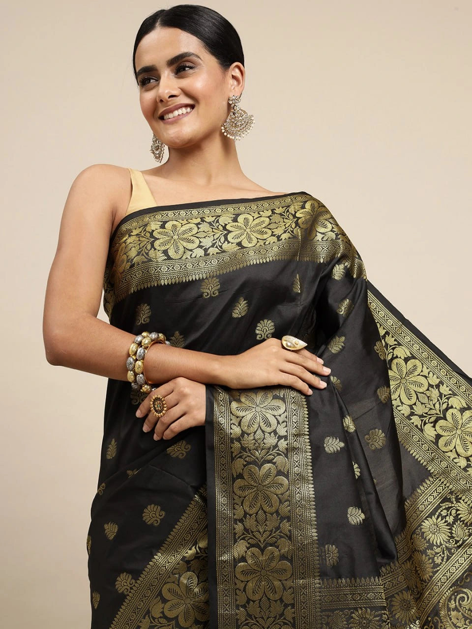 Woman wearing a black saree with gold patterns on a beige background