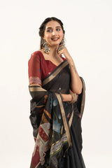 Woman wearing a black saree with a colorful pattern on a white background