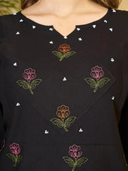 Black top with colorful floral embroidery on a blurred background