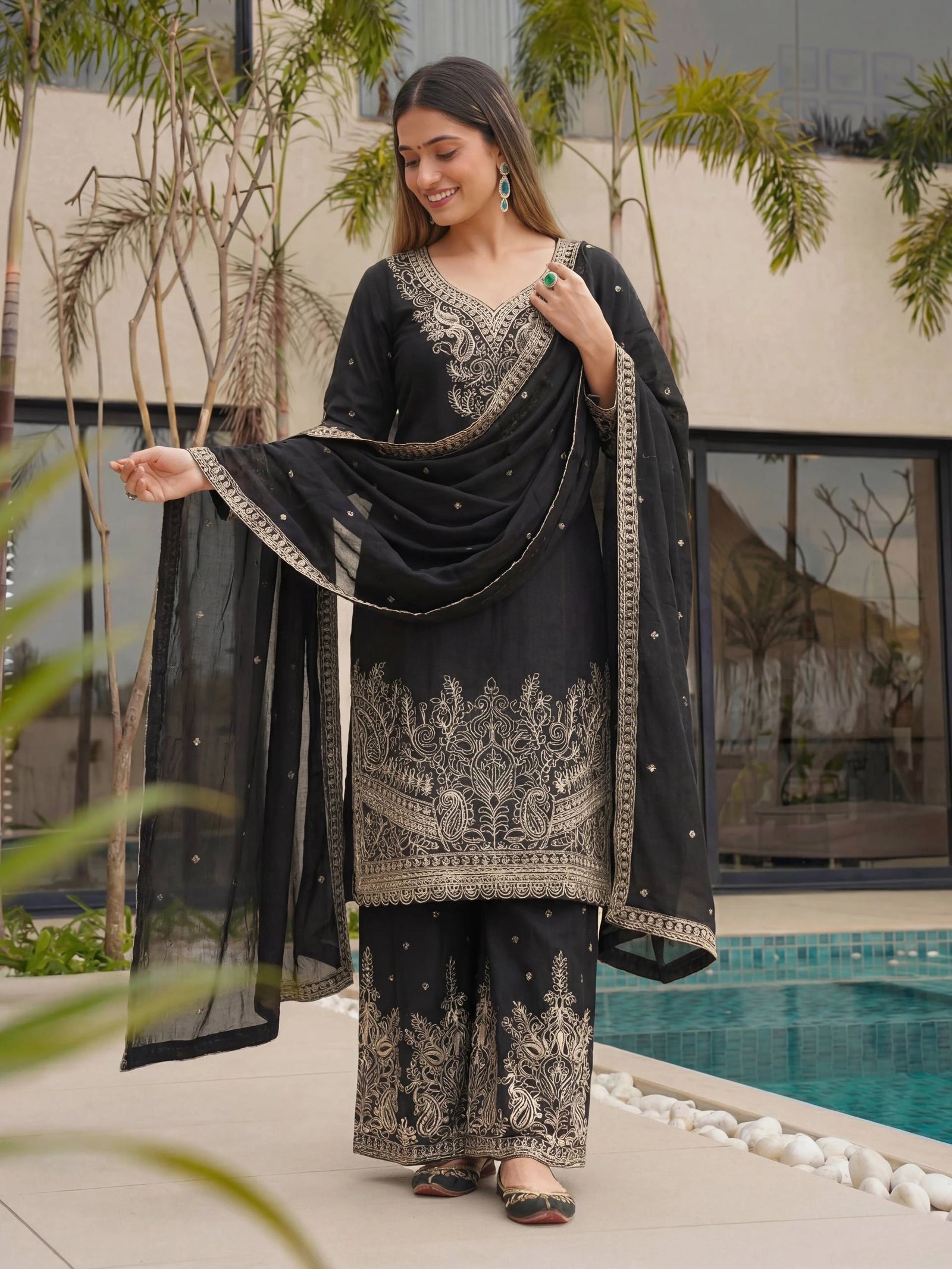 Woman in black and gold traditional outfit by a poolside