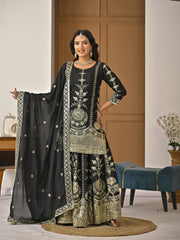 Woman in traditional black and gold embroidered outfit with a black dupatta in a well-lit room.