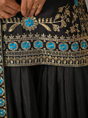 Close-up of a black garment with intricate gold and blue embroidery.