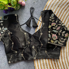 Black embroidered blouse on a textured surface with flowers in the background