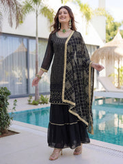 Woman in a black and gold traditional outfit standing by a pool.