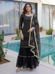 Woman in a black and gold traditional outfit standing by a pool.