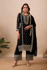 Woman wearing a black embroidered traditional outfit with gold details on a beige background