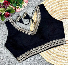 Black blouse with silver embroidery on a textured surface with flowers in the corner
