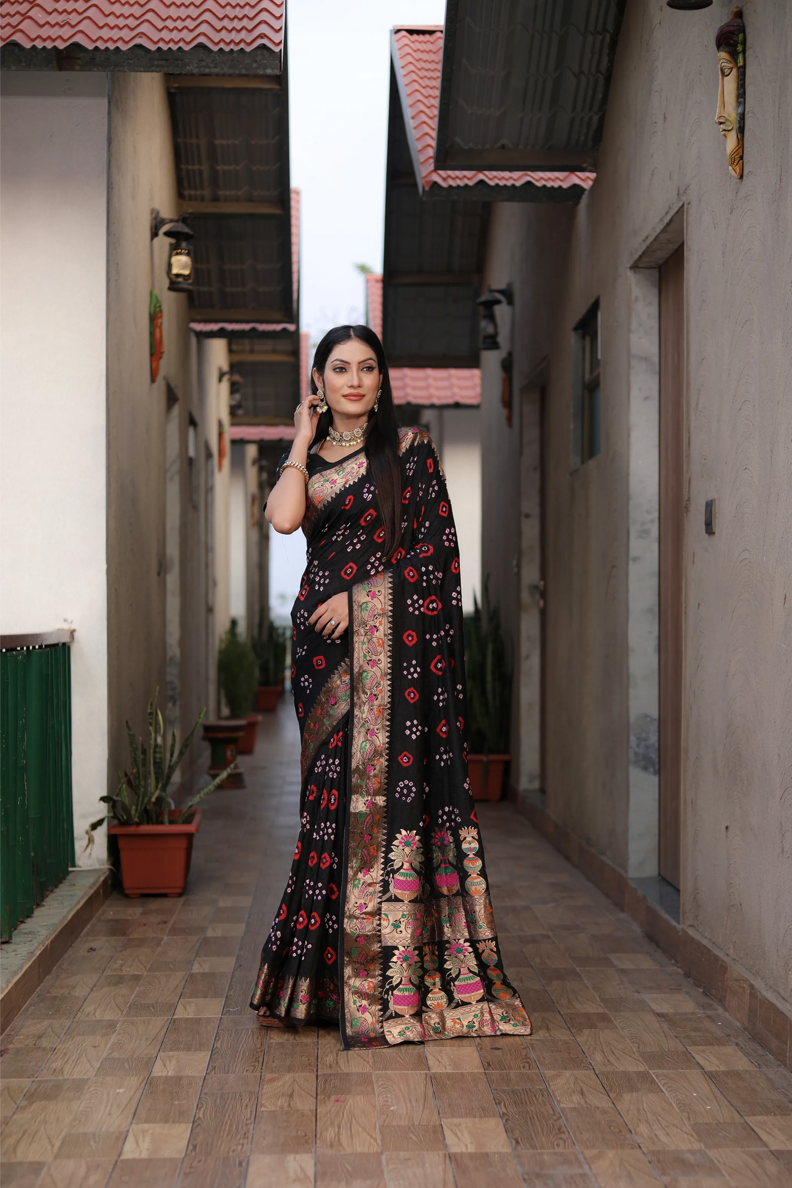 Woman wearing a pink saree with a colorful border outdoors.