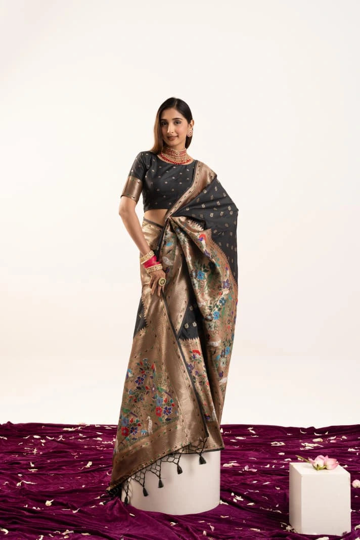 Woman wearing a black and gold saree with a floral pattern on a white background