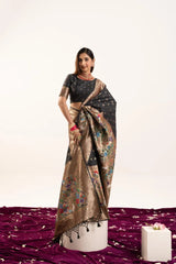 Woman wearing a black and gold saree with a floral pattern on a white background