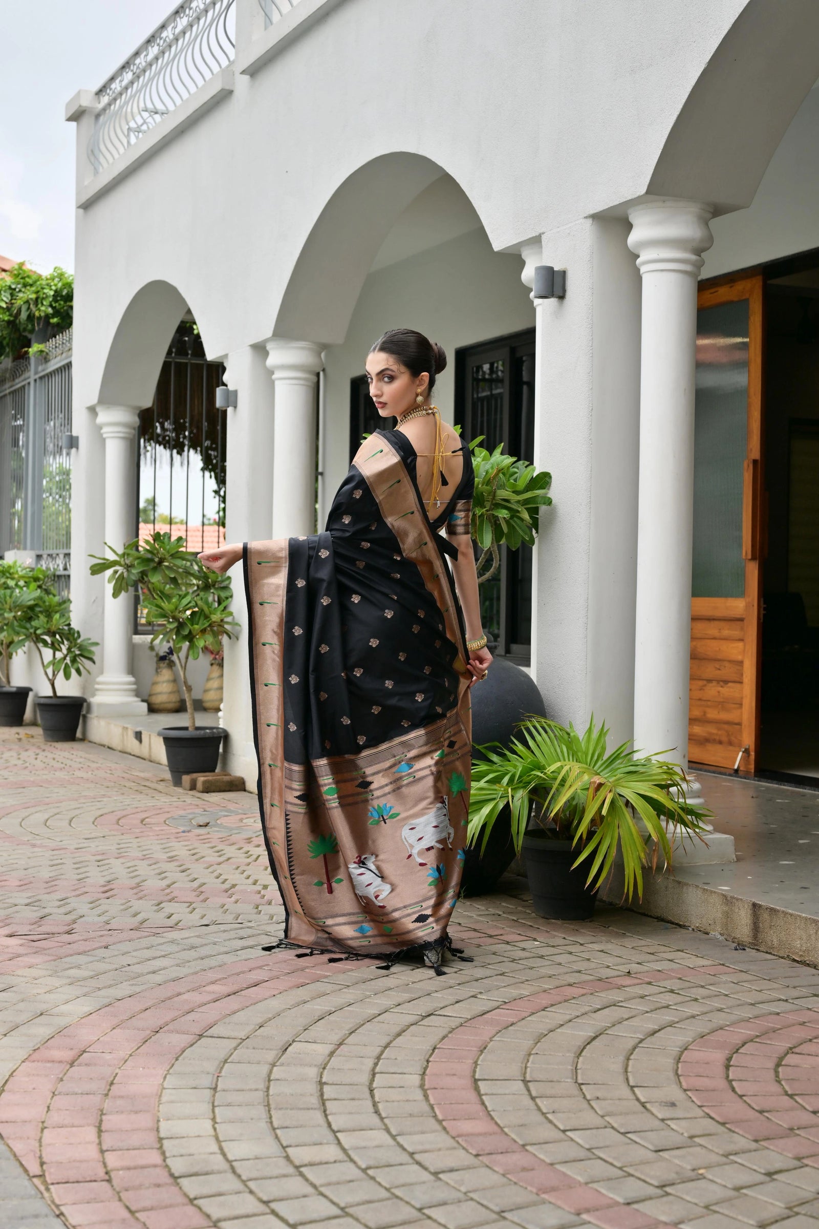 Woman in a saree standing in front of a white building with columns