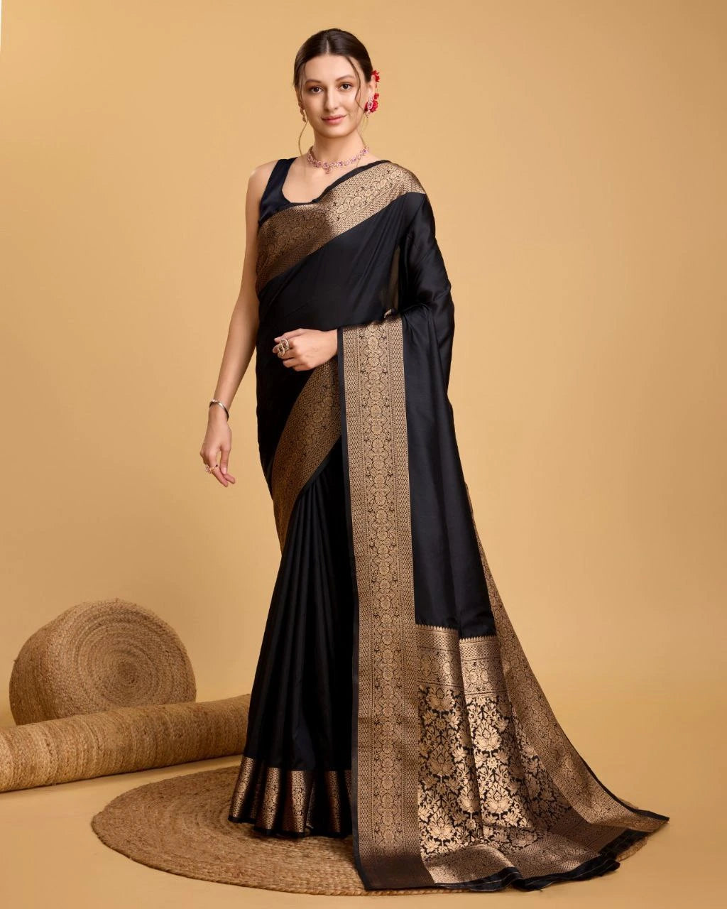 Woman wearing a black and gold saree with a beige background