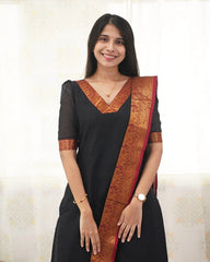 Woman wearing a black saree with a red border against a white background