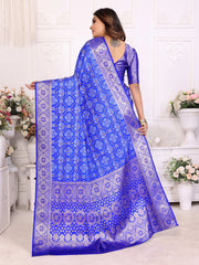 Woman wearing a blue saree with white patterns in a decorated room.