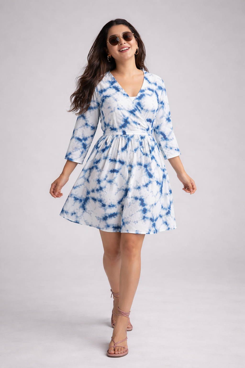 Woman wearing a blue and white tie-dye dress on a gray background