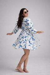 Woman wearing a tie-dye dress on a plain background