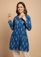 Woman wearing a blue patterned dress against a beige background