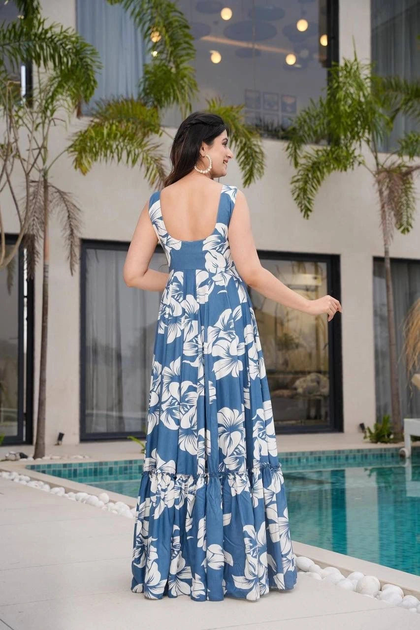 Woman in a blue floral dress standing by a pool with palm trees in the background