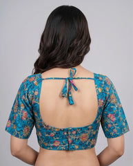 Woman wearing a blue floral blouse with an open back on a gray background