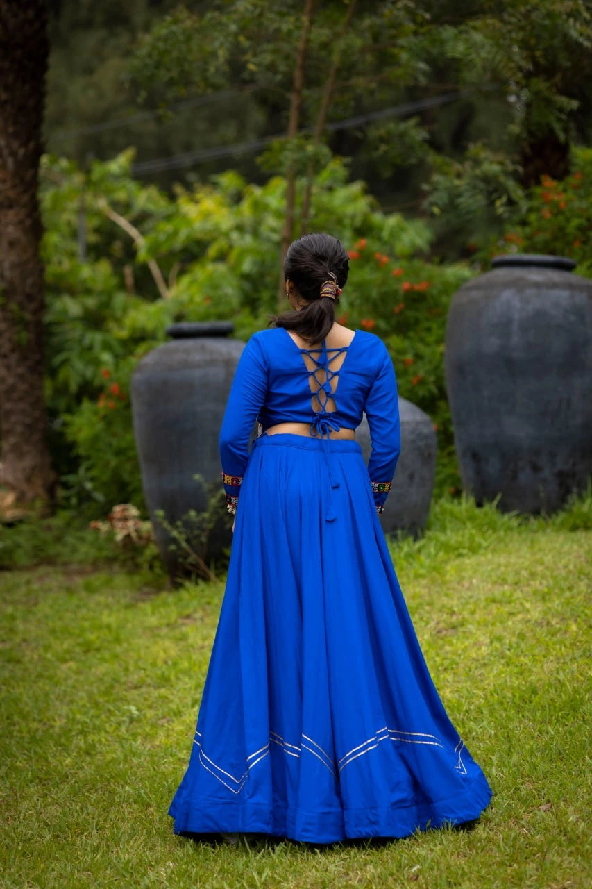 Person wearing a blue traditional outfit with a garden background