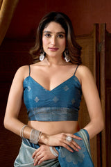 Woman wearing a blue saree with a matching blouse against a wooden background