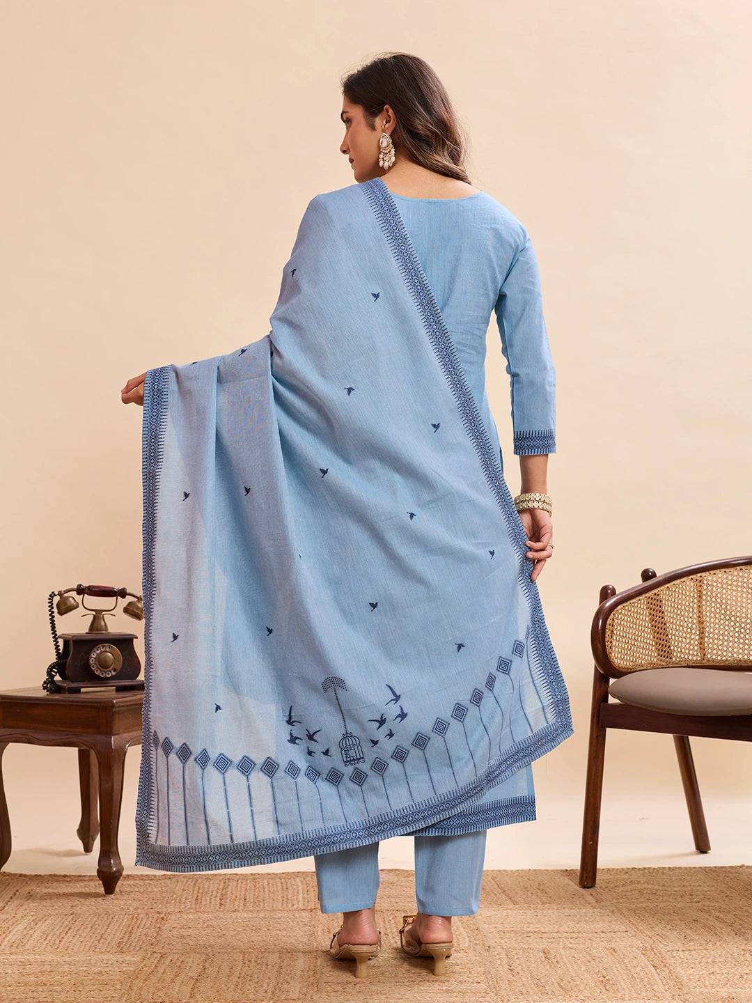 Woman wearing a light blue traditional outfit with a matching dupatta in a room setting.