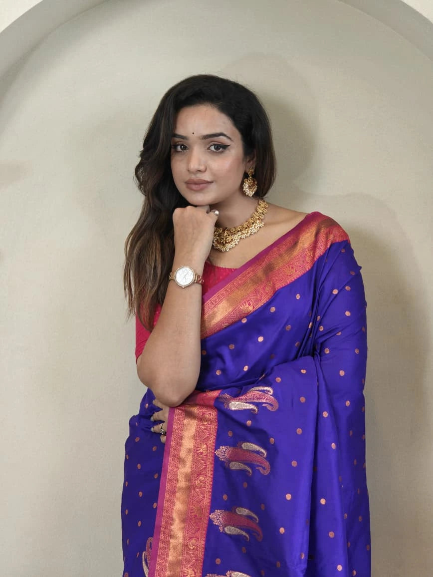 Woman wearing a blue saree with a pink blouse against a beige wall