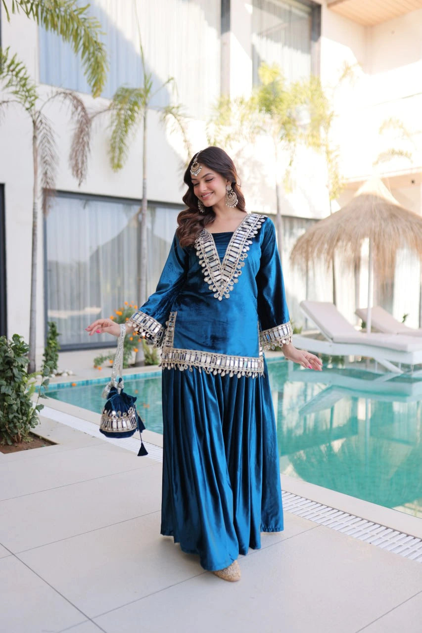 Woman in a blue traditional outfit standing by a pool with modern building and plants in the background