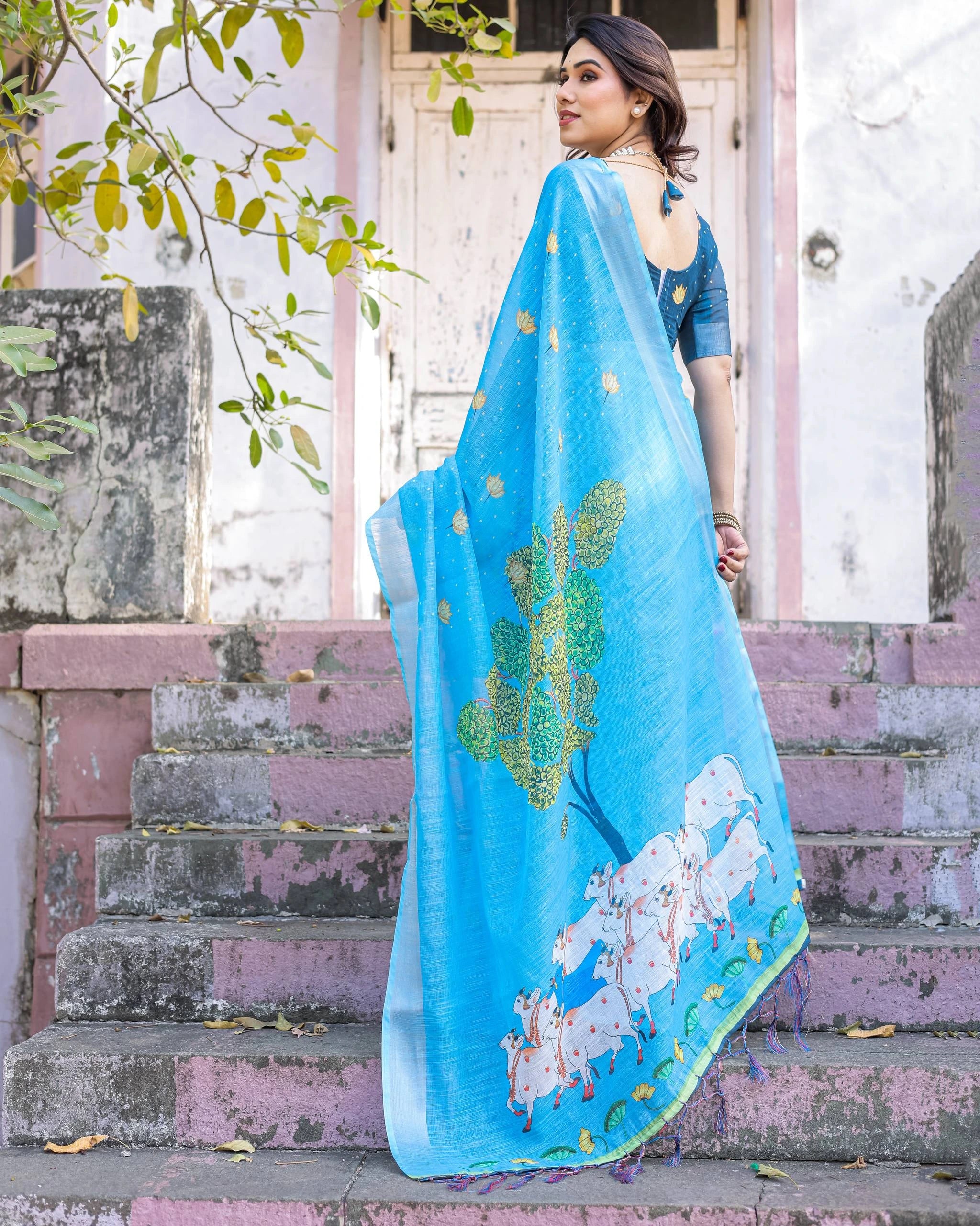 Woman wearing a blue saree with floral patterns on steps outdoors