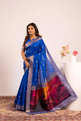 Woman wearing a blue saree with a colorful border against a white background