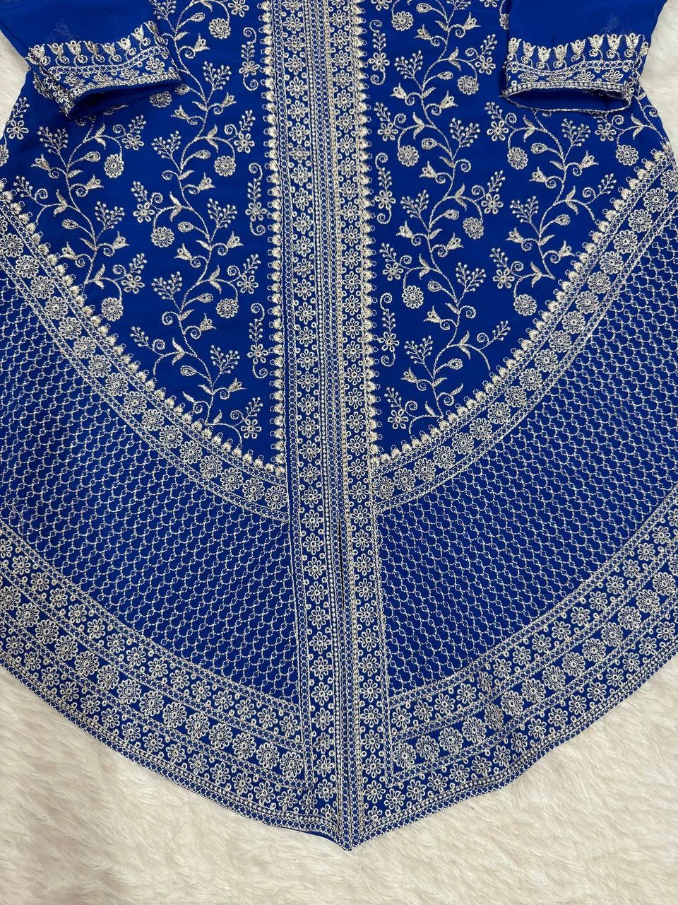 Blue fabric with intricate white embroidery on a white background