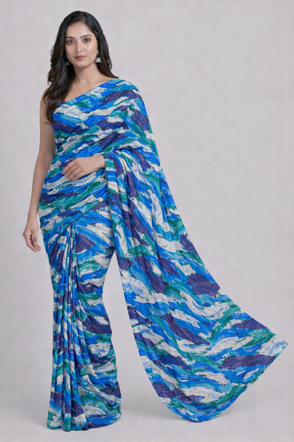 Woman wearing a blue and green patterned saree on a gray background