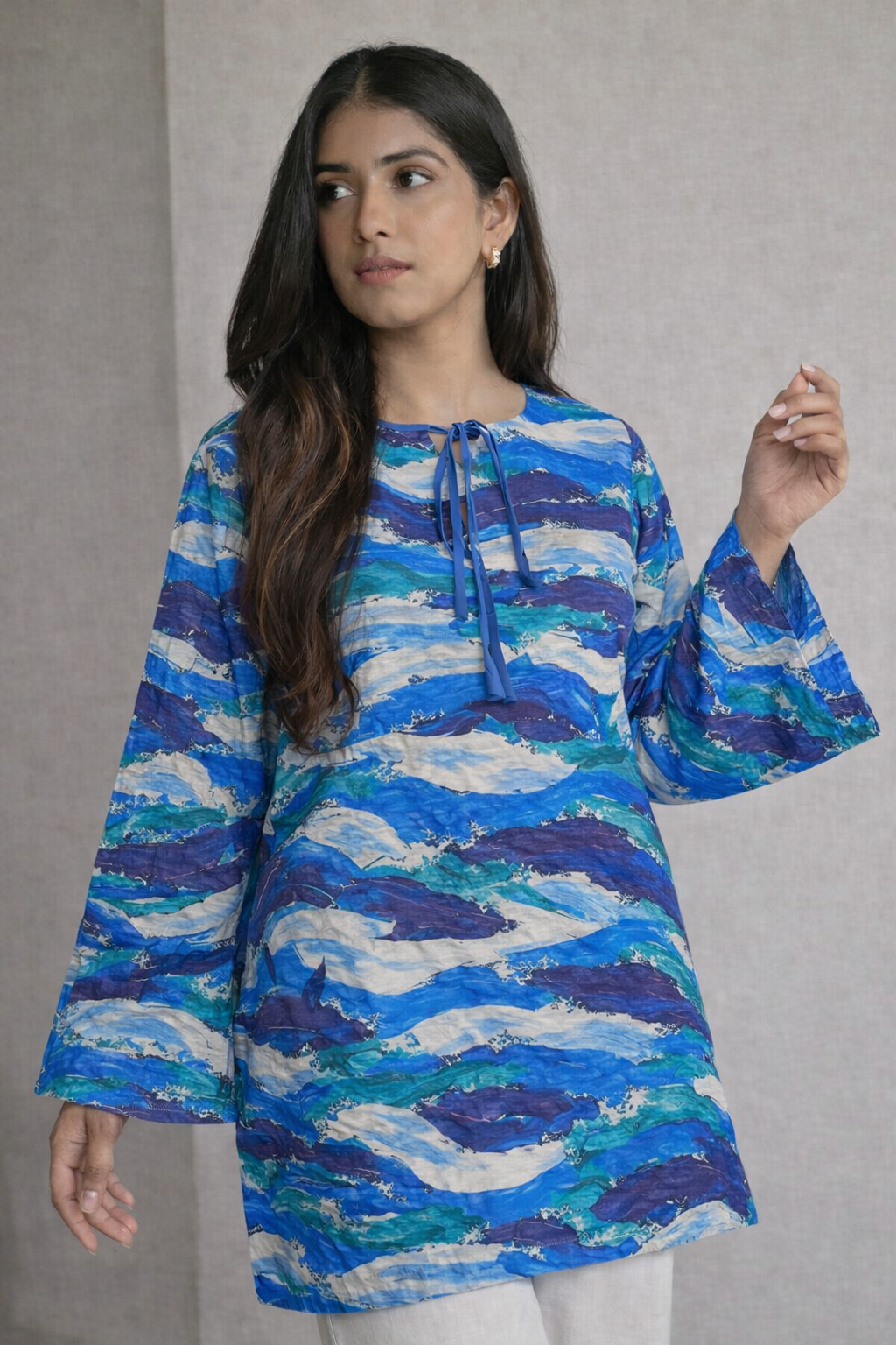 Woman wearing a blue and white patterned dress against a gray background