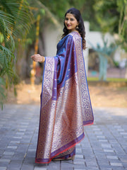Woman wearing a traditional saree with a blue and gold pattern, standing outdoors.