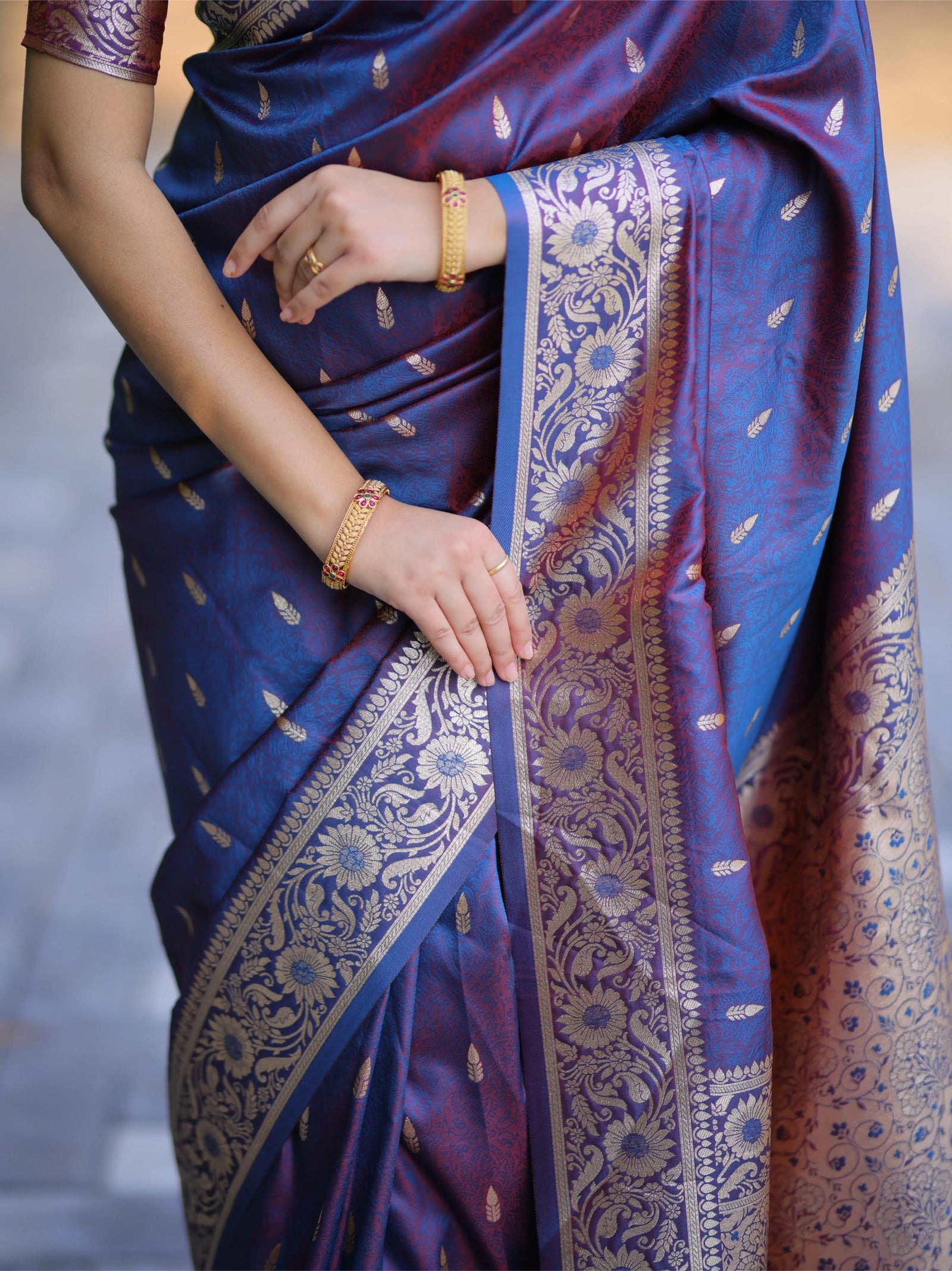 Blue saree with gold patterns worn by a person, against a neutral background