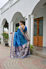 Woman in a blue saree standing in front of a white building with arches.