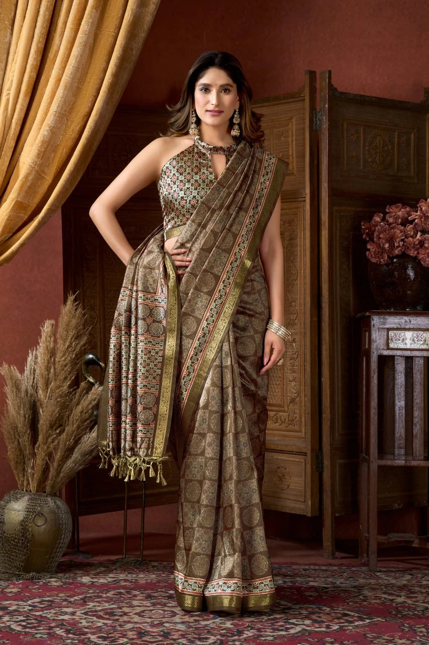 Woman in a patterned saree standing in an elegant room with decorative elements.