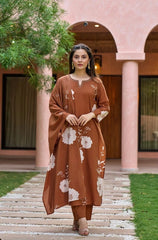 Woman in a brown floral dress standing in front of a building with arched windows.