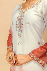 Close-up of a white and peach traditional outfit with intricate embroidery on a beige background