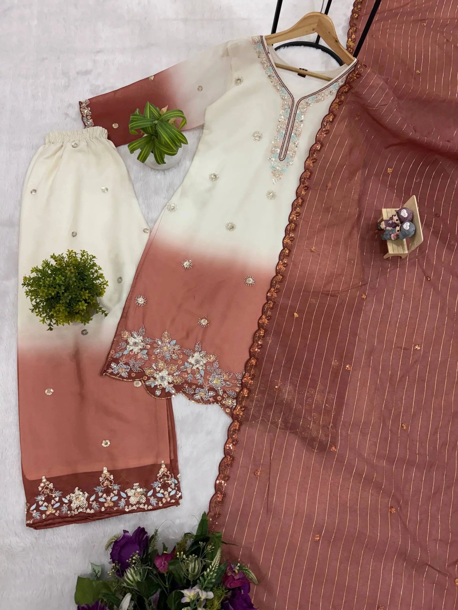 Traditional outfit with a white and brown dress on a hanger against a light background.