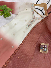 Embroidered fabric with a hanger on a surface with a plant in the background