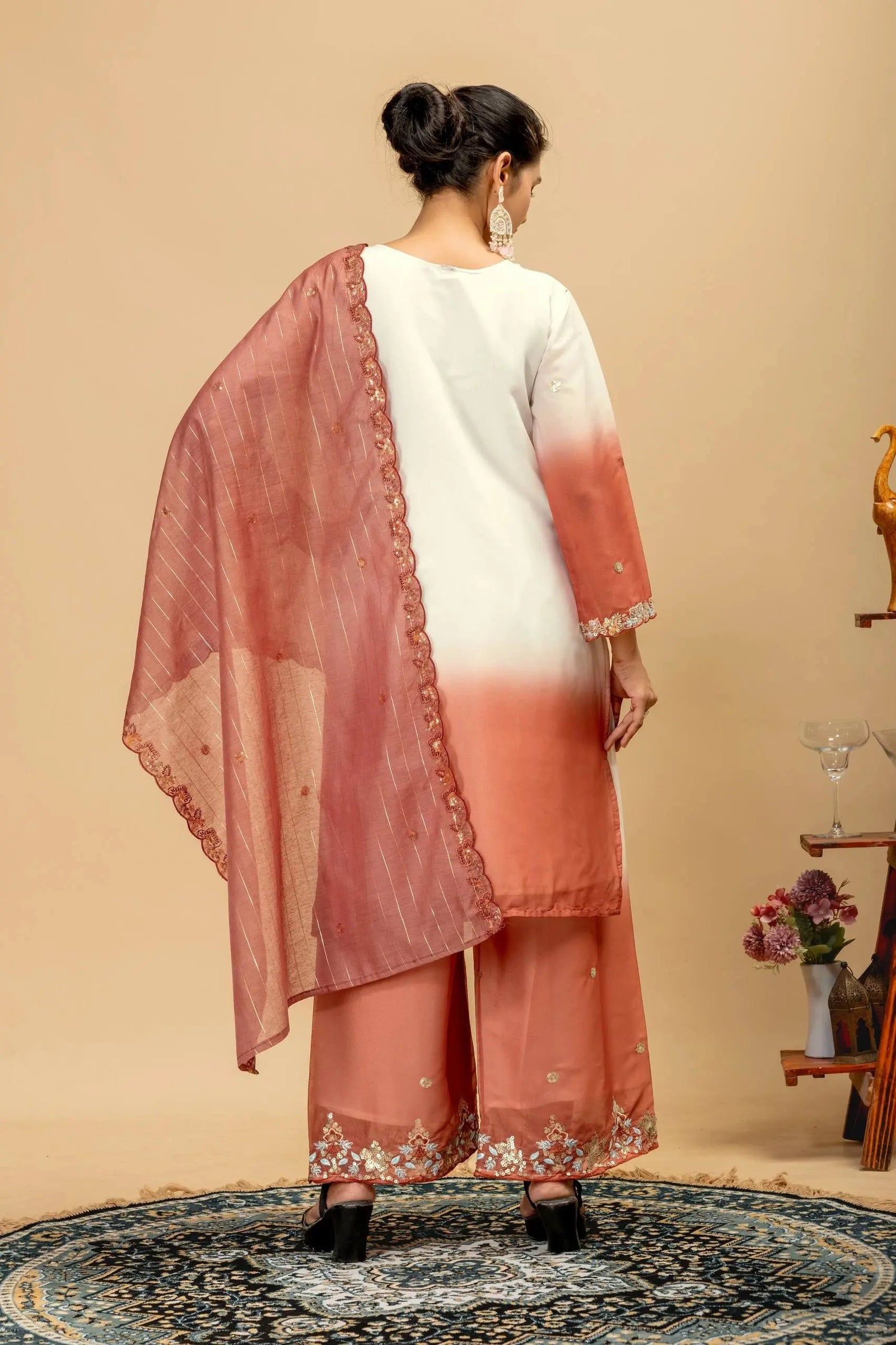 Woman wearing a traditional outfit with a pink dupatta and white top on a beige background