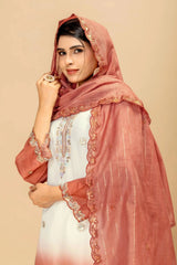 Woman wearing a white outfit with a pink embroidered dupatta against a beige background