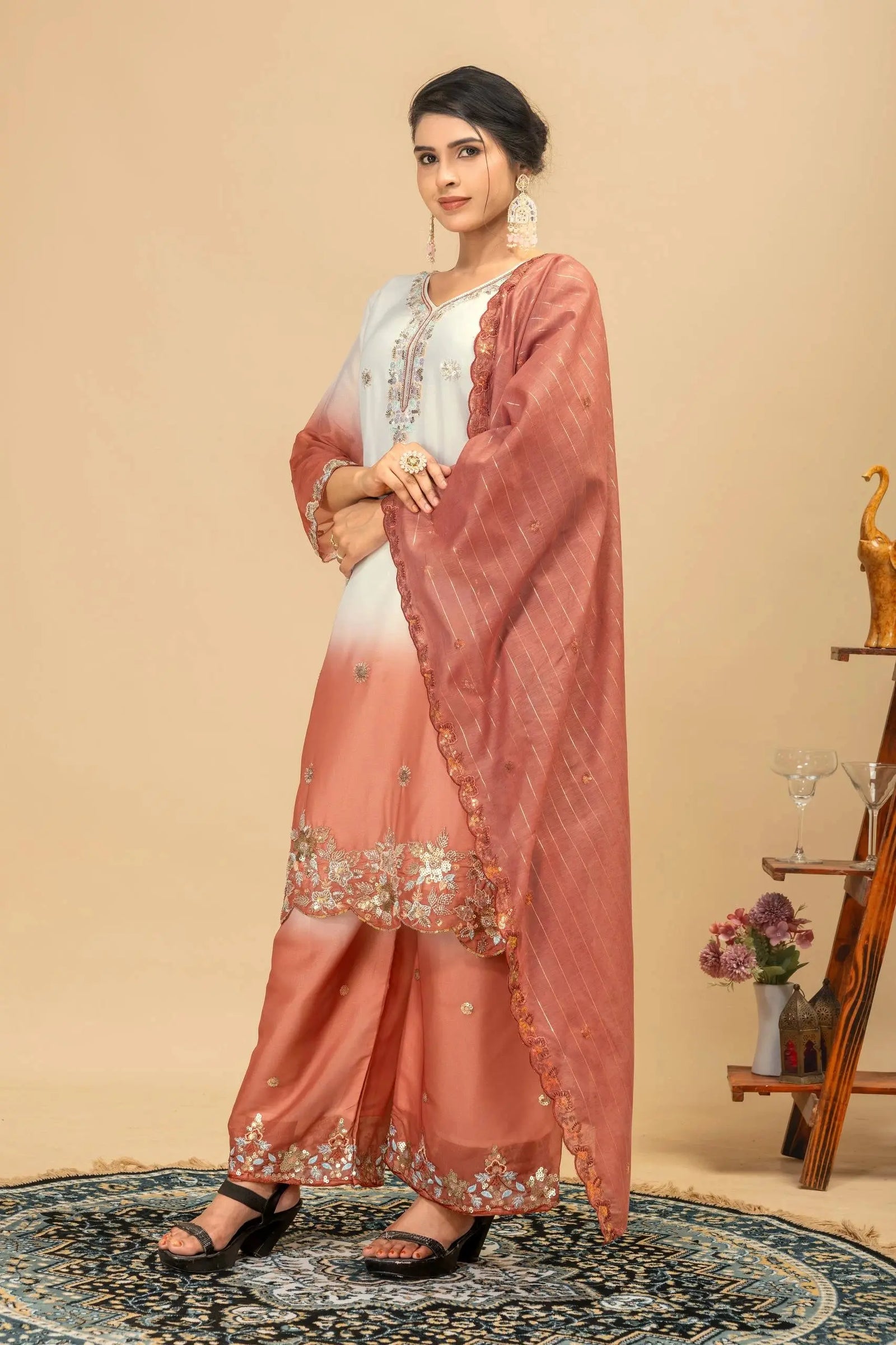 Woman wearing a traditional outfit with a pink dupatta and white blouse against a beige background