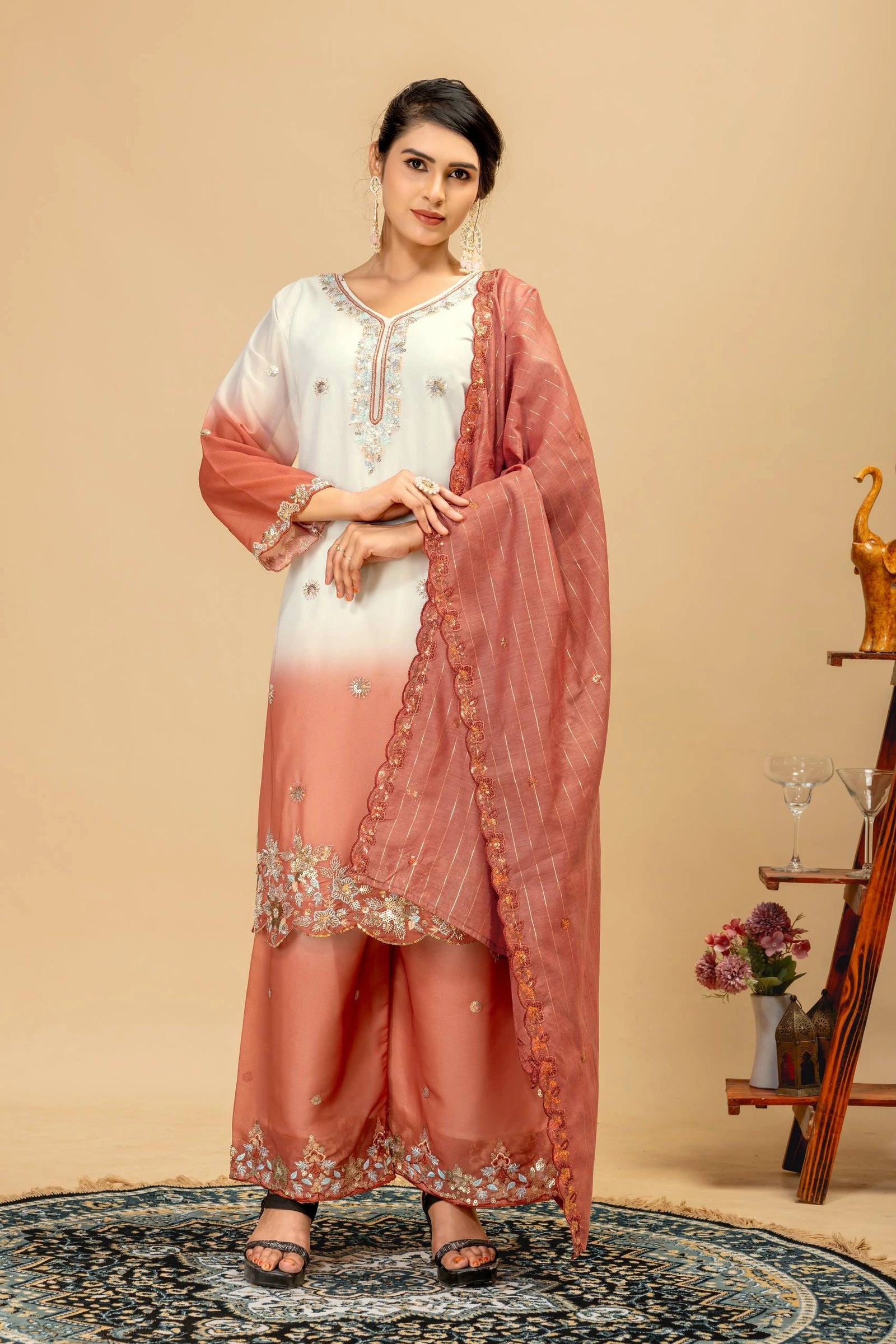 Woman wearing a peach and white traditional outfit with a matching dupatta against a beige background.