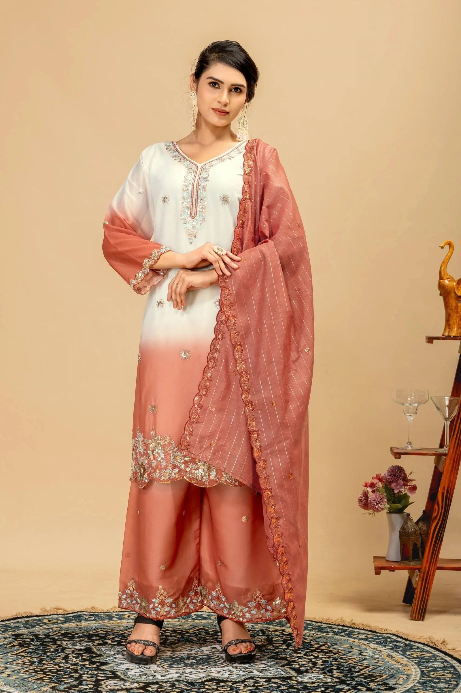 Woman wearing a peach and white traditional outfit with a matching dupatta against a beige background.