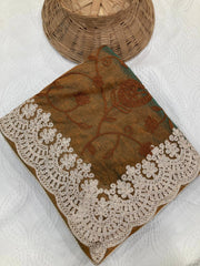 Brown fabric with floral embroidery and lace trim on a white background