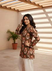 Woman wearing a floral brown top and white pants in a sunlit room.