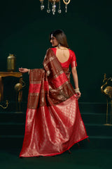 Woman in a red saree with gold patterns against a dark green background