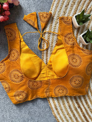 Yellow bikini top with intricate patterns on a textured surface.